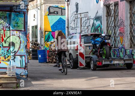 Riga, Lettonie - 30 septembre 2020 : un cycliste passe devant des peintures murales vibrantes dans une ruelle urbaine décorée de rues multiples Banque D'Images