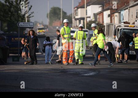 Les travailleurs d'intervention dégagent Sussex Road à Southport, dans le Merseyside, après que des policiers ont été grièvement blessés lorsque des briques, des pierres et des bouteilles ont été lancées et que des voitures ont été incendiées lors de violentes manifestations suite à une veillée pour trois filles tuées dans une attaque au couteau dans un club de vacances sur le thème de Taylor Swift lundi. Date de la photo : mercredi 31 juillet 2024. Banque D'Images