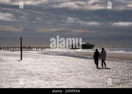 Une journée à la mer des Wadden. Silhouettes de marcheurs de plage et de familles profitant d'une sortie à la plage de Sankt Peter-Ording un jour de printemps. Banque D'Images