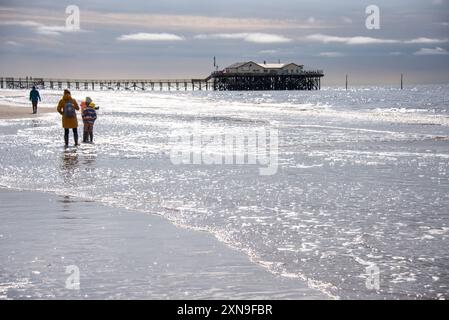 Une journée à la mer des Wadden. Silhouettes de marcheurs de plage et de familles profitant d'une sortie à la plage de Sankt Peter-Ording un jour de printemps. Banque D'Images