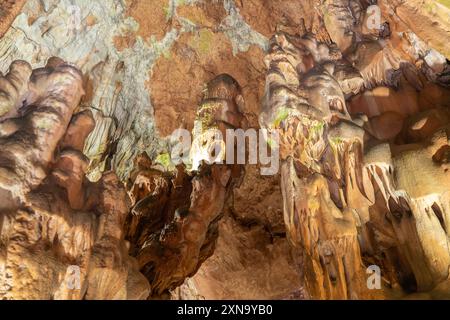 Une grotte avec beaucoup de formations rocheuses et un petit trou au milieu. La grotte est sombre et la lumière vient du trou. Banque D'Images
