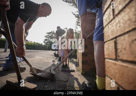 ***AUTORISATION PARENTALE ACCORDÉE*** des volontaires balayent Sussex Road à Southport, Merseyside, après que des policiers aient été gravement blessés lorsque des briques, des pierres et des bouteilles ont été lancées et que des voitures ont été incendiées lors de violentes manifestations suite à une veillée pour trois filles tuées dans une attaque au couteau dans un club de vacances sur le thème de Taylor Swift lundi. Date de la photo : mercredi 31 juillet 2024. Banque D'Images