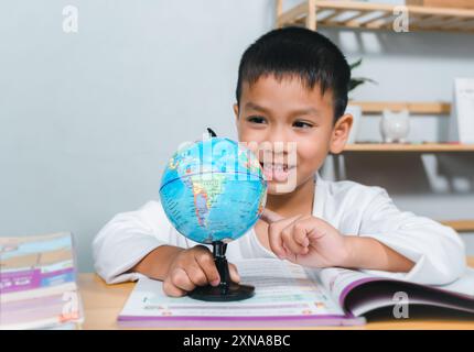 Garçon asiatique regardant et pointant votre doigt sur le globe trouver l'emplacement des pays dans le monde, concept pour la recherche réchauffement climatique, réseau mondial, SEO Banque D'Images