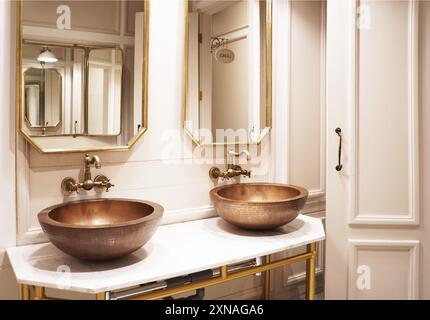 une salle de bains luxueuse avec deux grands lavabos en cuivre martelés sur un marbre blanc Banque D'Images