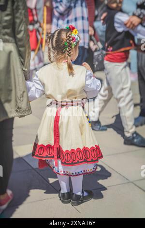 Petite fille en vêtements bulgares nationaux au festival folklorique, vue arrière Banque D'Images