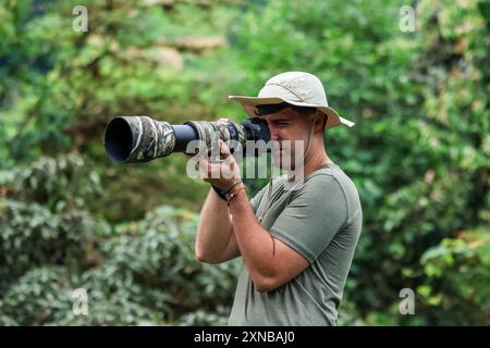 photographe de la nature, portant un chapeau d'explorateur, capture des images de la faune dans la jungle à l'aide d'un appareil photo et d'un téléobjectif. met en évidence l'aventure an Banque D'Images