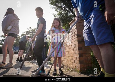 RETRANSMISSION EN AJOUTANT DES INFORMATIONS SUPPLÉMENTAIRES SUR LA LÉGENDE ***PERMISSION PARENTALE ACCORDÉE *** Sebastian Taylor, 10 ans, et sa sœur Evelyn, 7 ans, ont aidé à balayer Sussex Road à Southport, Merseyside, après que des policiers ont subi de graves blessures lorsque des briques, des pierres et des bouteilles ont été lancées et des voitures incendiées lors de violentes manifestations à la suite d'une veillée en faveur de trois filles tuées dans une attaque au couteau dans un club de vacances sur le thème de Taylor Swift lundi. Date de la photo : mercredi 31 juillet 2024. Banque D'Images