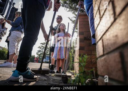 RETRANSMISSION EN AJOUTANT DES INFORMATIONS SUPPLÉMENTAIRES SUR LA LÉGENDE ***PERMISSION PARENTALE ACCORDÉE *** Evelyn Taylor, âgée de sept ans, aide à balayer Sussex Road à Southport, Merseyside, après que les policiers aient subi de graves blessures lorsque des briques, des pierres et des bouteilles ont été lancées et des voitures incendiées lors de violentes manifestations à la suite d'une veillée en faveur de trois filles tuées dans une attaque au couteau dans un club de vacances sur le thème de Taylor Swift lundi. Date de la photo : mercredi 31 juillet 2024. Banque D'Images