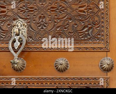 Ancienne porte en bois décorée d'ornements arabes sculptés avec un frappeur de porte Banque D'Images