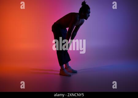 Un jeune homme afro-américain danse sur un fond dégradé coloré. Banque D'Images