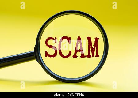 Loupe se concentrant sur le texte d'ARNAQUE sur fond de couverture jaune. Concept de cybersécurité. Banque D'Images