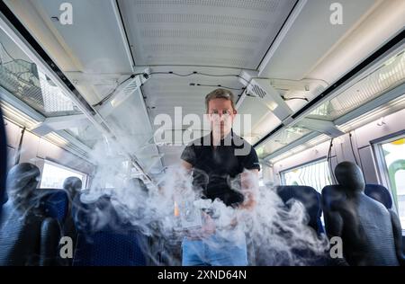 Minden, Allemagne. 31 juillet 2024. Daniel Schmeling, du Centre aérospatial allemand (DLR), pulvérise de la fumée dans le compartiment du train avec une machine à fumée dans un wagon d'essai de la Deutsche Bahn pour tester la turbulence de l'air pour les passagers. Le Centre aérospatial allemand (DLR) de Göttingen mène des recherches sur les systèmes de climatisation des trains dans un wagon d'essai Deutsche Bahn. Crédit : Guido Kirchner/dpa/Alamy Live News Banque D'Images