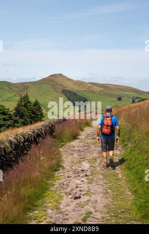 Homme marchant à dos le long d'une piste de campagne vers le Cheshire mini montagne Shutlingsloe dans le district de White Peak Angleterre Banque D'Images