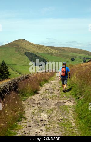 Homme marchant à dos le long d'une piste de campagne vers le Cheshire mini montagne Shutlingsloe dans le district de White Peak Angleterre Banque D'Images