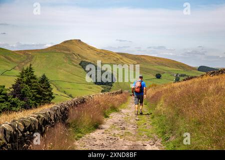 Homme marchant à dos le long d'une piste de campagne vers le Cheshire mini montagne Shutlingsloe dans le district de White Peak Angleterre Banque D'Images