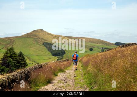 Homme marchant à dos le long d'une piste de campagne vers le Cheshire mini montagne Shutlingsloe dans le district de White Peak Angleterre Banque D'Images