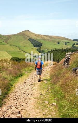 Homme marchant à dos le long d'une piste de campagne vers le Cheshire mini montagne Shutlingsloe dans le district de White Peak Angleterre Banque D'Images