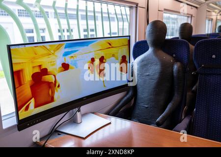 Minden, Allemagne. 31 juillet 2024. Dans un wagon d'essai Deutsche Bahn, un mannequin se trouve à côté d'un écran affichant l'image d'une caméra thermique. Le Centre aérospatial allemand (DLR) de Göttingen mène des recherches sur les systèmes de climatisation des trains dans un wagon d'essai Deutsche Bahn. Crédit : Guido Kirchner/dpa/Alamy Live News Banque D'Images