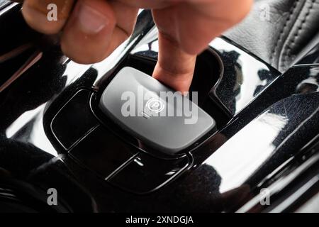 Appuyez à la main sur le bouton de frein à main électronique dans la voiture moderne de luxe Banque D'Images