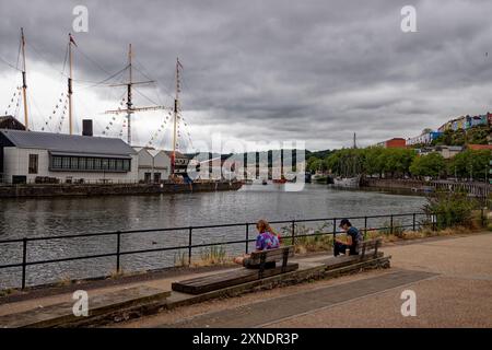 Deux personnes assises au bord de l'eau du port de Bristol. Banque D'Images