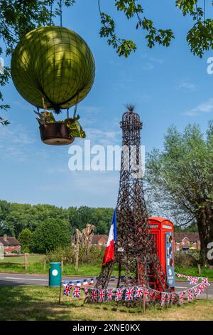 31 juillet 2024. Un coffret téléphonique rouge décoré pour célébrer les Jeux Olympiques de Paris. Les décorations des Jeux Olympiques comprennent un grand modèle de la Tour Eiffel à côté de la boîte téléphonique rouge traditionnelle avec le Chaudron olympique ou la flamme montgolfière dans un arbre voisin. Banque D'Images