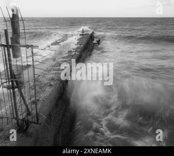 Ralenti des vagues qui frappent un brise-vagues Banque D'Images