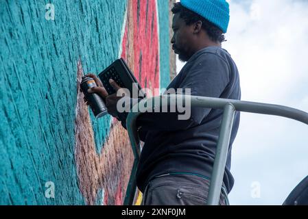 Breeze Yoko travaille sur sa nouvelle pièce qui doit être finie avant le début du Soul Festival le vendredi 2 août à Margate. Rise Up Residency (organisation locale basée à Margate) et Breeze Yoko se sont associés pour réaliser de nouvelles peintures murales sur le mur du Lido Margate pour le Festival de l'âme Margate. Breeze Yoko est une artiste multidisciplinaire de renommée mondiale basée en Afrique du Sud et conservatrice qui a participé à des projets urbains à travers le monde comme le Sénégal, le Mozambique, le Botswana, l'Afrique du Sud, l'Allemagne, France, Suède, Royaume-Uni et beaucoup d'autres endroits. Banque D'Images