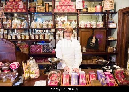 COMTÉ DE DURHAM, ROYAUME-UNI - 10 OCTOBRE 2023. Femme vêtue de vêtements traditionnels victoriens. Commerçant dans une boutique de bonbons, musée Beamish, Durham, Royaume-Uni Banque D'Images