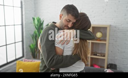 Un couple aimant embrasse dans un salon confortable, exprimant l'affection et la convivialité dans un cadre confortable à la maison. Banque D'Images