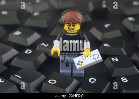 Tambov, Fédération de Russie - 31 juillet 2024 Une figurine Lego Video Game Guy avec manette de jeu debout dans une pile de touches noires du clavier d'ordinateur. Banque D'Images