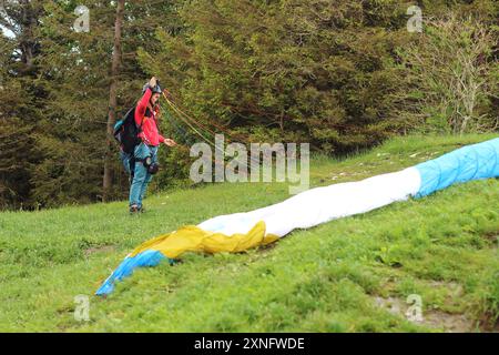 Une femme parapente complète ses derniers préparatifs avant de décoller d'une montagne du sud de la Bavière. La scène capture l'anticipation et le thril Banque D'Images