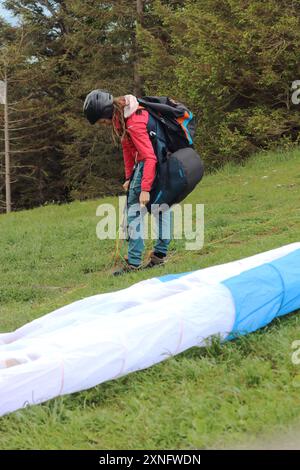 Une femme parapente complète ses derniers préparatifs avant de décoller d'une montagne du sud de la Bavière. La scène capture l'anticipation et le thril Banque D'Images