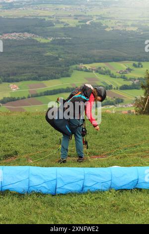 Une femme parapente complète ses derniers préparatifs avant de décoller d'une montagne du sud de la Bavière. La scène capture l'anticipation et le thril Banque D'Images