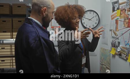 Une femme et un homme, en tenue professionnelle, analysent les preuves sur un tableau dans le bureau d'un détective. Banque D'Images