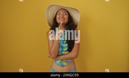 Belle femme chinoise en maillot de bain et chapeau posant sur fond jaune Banque D'Images