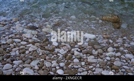 Des galets de différentes tailles et couleurs sont doucement lavés par les vagues sur une plage rocheuse sur la côte méditerranéenne. Banque D'Images