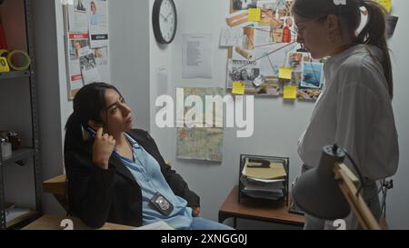 Deux femmes enquêtrices analysent les preuves dans un bureau de poste de police, entourées de cartes et de dossiers. Banque D'Images