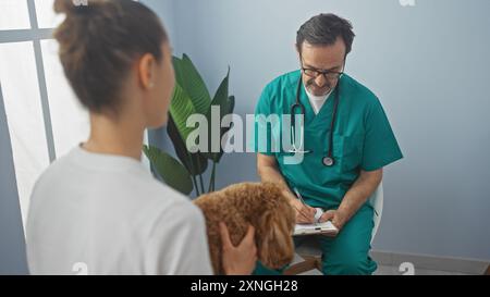 L'homme vétérinaire hispanique examine le caniche du patient dans une salle de clinique, fournissant des conseils de soins à une jeune femme. Banque D'Images