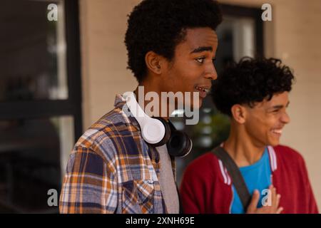 Adolescents souriants et parlant à l'extérieur du bâtiment du lycée, portant des vêtements décontractés Banque D'Images