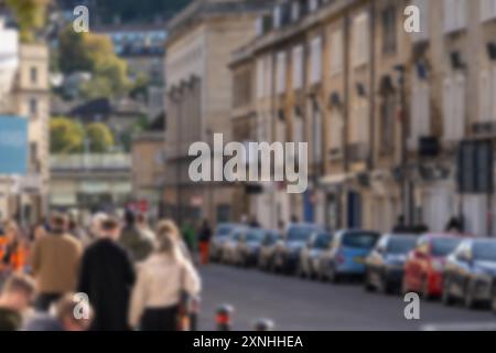 Une image floue de gens marchant dans une rue dans une ville. Ils passent devant une rangée de voitures garées devant un vieux bâtiment. Banque D'Images