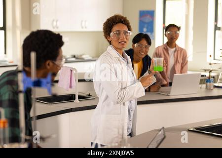 Dans le laboratoire du lycée, enseignant démontrant l'expérience avec bécher aux élèves Banque D'Images