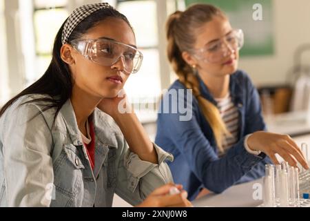 Port de lunettes de sécurité, adolescentes menant des expériences scientifiques dans une classe de lycée Banque D'Images