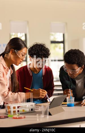 Réalisation d'expériences scientifiques, adolescents utilisant des tablettes et des équipements de laboratoire au lycée Banque D'Images