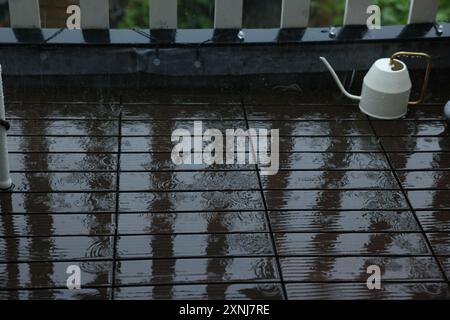 Arrosoir sur le balcon mouillé pendant la pluie Banque D'Images