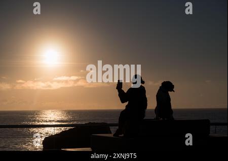 Le magnifique lever de soleil doré sur un horizon océanique à 'The Spit' sur Surfers Paradise a magnifiquement silhouetté un propriétaire et leur chien. Banque D'Images