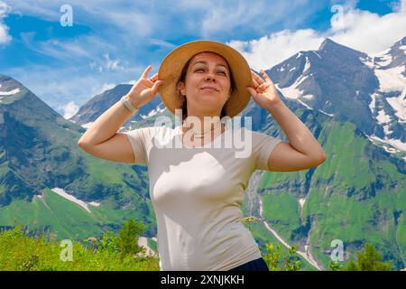 Une femme dans un chapeau de paille jouit d'une vue sur les montagnes alpines par une journée ensoleillée Banque D'Images
