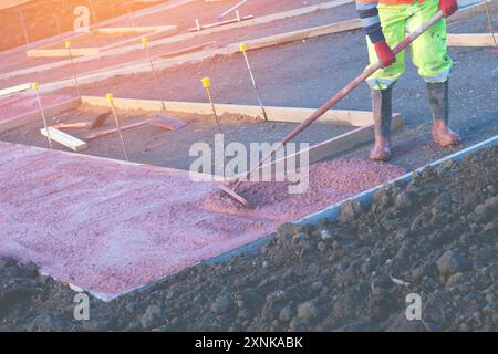 Constructeurs coulant et nivelant du béton prêt à l'emploi humide dans le coffrage lors de la construction d'un nouveau sentier Banque D'Images