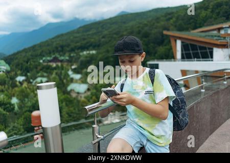 Garçon caucasien utilisant un message texte sur smartphone. Voyager en montagne Banque D'Images