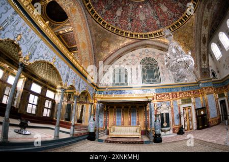 ISTANBUL, Turquie / Türkiye — L'opulente salle du trône impérial dans le harem du palais de Topkapi, Istanbul. Cette chambre richement décorée, ornée de carreaux Iznik complexes, d'ornements dorés et de riches meubles, servait de salle d'audience privée pour le sultan ottoman dans les limites isolées du harem impérial. La salle reflète la maîtrise artistique et le luxe de l'architecture impériale ottomane, offrant un aperçu du monde de la cour ottomane. Banque D'Images