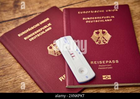 Augsbourg, Bavière, Allemagne - 1er août 2024 : test COVID-19 positif aux côtés de deux passeports. Image symbolique annulation des vacances d'été prévues en raison d'une maladie à coronavirus en été. PHOTOMONTAGE *** positionneur Ein COVID-19 test neben zwei Reisepässen. Symbolbild Absage des geplanten Sommerurlaub aufgrund einer Coronavirus Erkrankung im Sommer. FOTOMONTAGE Banque D'Images